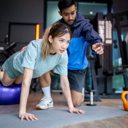 Asian man and woman working out, one is a trainer, the other is an exerciser